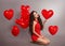 Pretty cute brunette girl in red with heart balloons posing isol