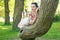 Pretty cute young brunette woman posing with her lovely tree in the green summer garden alone. happy girl pleasure in the nature,