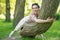 Pretty cute young brunette woman posing with her lovely tree in the green summer garden alone. happy girl pleasure in the nature,