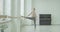 Pretty dancer warming up at barre in ballet studio