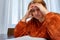 Pretty desperate adult businesswoman reviewing bills at the table in her living room. Selective focus