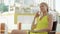 Pretty dreamy young woman in yellow dress sitting on chair near swimming pool twisting her hair