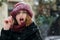 Pretty emotional woman wearing red cap posing at the street during snowfall. Space for text