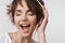 Pretty excited happy woman posing isolated over white wall background listening music with headphones