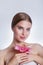 Pretty face of beautiful young woman with pink lily on hands. Concept for skin care or organic cosmetics