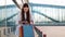 Pretty fashion model in white dress poses with shopping bags before a modern glass building