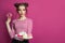 Pretty fashion model woman giving plate with dessert sweets snacks on vivid pink background