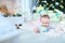 Pretty female baby lying on floor on blanket with present near twinkling Christmas tree.