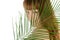 Pretty female behind palm leaf