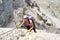 Pretty female climber in lilac shirt on a steep Via Ferrata in the italian Dolomites