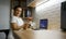 Pretty female doctor holds a dental impression of human jaw looking at camera sitting in front of a laptop with panoramic X-ray