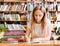 Pretty female student with books working in a high school library