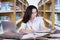 Pretty female student doing schoolwork in library