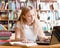 Pretty female student typing on notebook in library