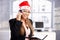 Pretty female wearing santa hat smiling in office