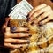 Pretty fingers of african american woman holding money close up with purse, luxury jewellery on python clutch, cash for