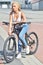 Pretty fitness girl with sport bike is walking in the city