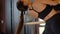 Pretty flexible girl with ponytail in black top bends body backward with leg on ballet handrail closeup slow motion