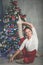 Pretty flexible woman is doing stretching near christmas tree, sports and holiday concept