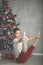 Pretty flexible young woman is doing sports near christmas tree, sports and holiday concept