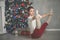 Pretty flexible young woman is doing sports near christmas tree, sports and holiday concept