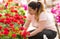 Pretty florists woman working with blooming flowers at a greenhouse