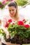 Pretty florists woman working with blooming flowers at a greenhouse