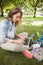 Pretty focused student sitting on grass using laptop