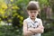 Pretty funny moody little blond preschool girl in white sleeveless dress looks into camera feeling angry and unsatisfied on