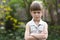 Pretty funny moody little blond preschool girl in white sleeveless dress looks into camera feeling angry and unsatisfied on