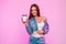 Pretty funny young woman in fashionable blue denim jacket in stylish white t-shirt with cup of tasty drink posing near pink wall