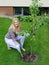 Pretty gardener woman planting apple tree