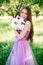 Pretty gentle young girl in a purple dress poses in an apple garden with a bouquet in her hands. Professional makeup and