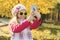 Pretty girl of 7 years doing selfie using smartphone, autumn background.