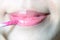 Pretty girl applying lipstick cream to her mouth