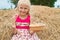 Pretty girl with bread sitting on a haystack.