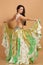 A pretty girl brunette who dances go-go and belly dance, stretching posing in studio in green arabian dress on a beige background