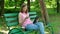 Pretty girl buy online sitting on the bench in the park. Happy women shopping via internet use tablet at the open air