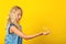 Pretty girl catch soap bubble over yellow background. Blonde girl with curly healthy hair. Summer fashion