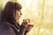 Pretty Girl drinking Coffee or Tea near Window. Warm colors toned