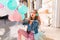 Pretty girl with long hair wearing pink pants sending kiss while waiting for party sitting on the street. Charming young