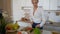 Pretty girl preparing salad of fresh vegetables on cutting board in modern kitchen.