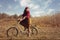 Pretty girl riding bicycle in field