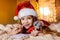 a pretty girl in a Santa hat writes a letter to Santa on the eve of Christmas, at home, lights and bokeh