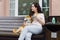 Pretty girl sitting in street cafe with cup of tea and shiba inu dog smiling