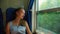 Pretty girl sleeps in train near window and smiles