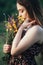 Pretty girl smell flowers in bouquet in hands , young woman with long hair in dress walking on nature,summer tender photo in