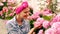 Pretty girl smelling pink hydrangea bunch in the backyard. Woman gardening - happy female gardener taking care of
