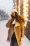 Pretty girl smiling in front of warm city lights in winter