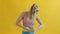 Pretty girl in sportswear measuring waist with measure-tape and smiling on yellow background